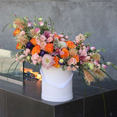 Large mixed floral arrangement in a white vase with pink and orange blooms