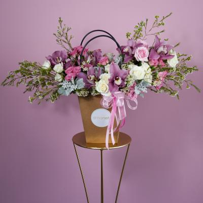 Pink and white flower arrangement in a brown handled box with ribbon
