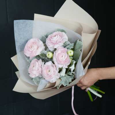 Hand-tied bouquet of pale pink ranunculus in beige and white paper