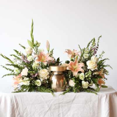 Floral centerpiece with lilies and roses around a gold urn