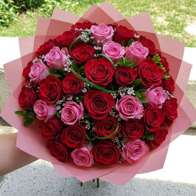 Round bouquet of red and pink roses wrapped in pink paper