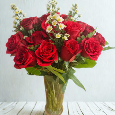 Bouquet of red roses with small white filler flowers in a glass vase