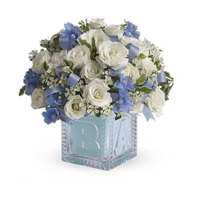 White rose and blue flower arrangement in a glass baby block cube vase with blue ribbon accents