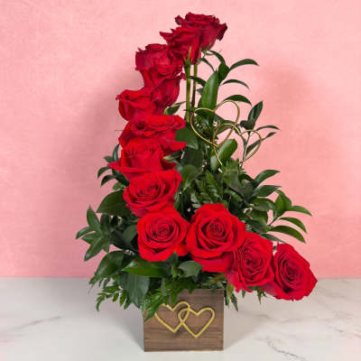 Red roses arranged in a wooden box with gold heart accents