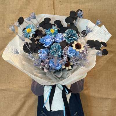 Bouquet of blue flowers with black foliage wrapped in white paper