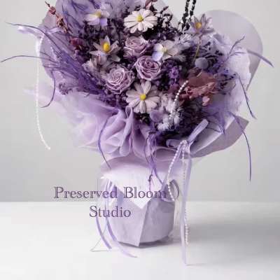 Lavender bouquet with roses and daisy-like flowers wrapped in purple paper