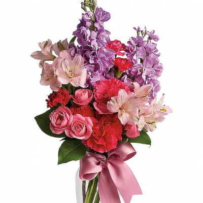 Pink and purple mixed bouquet in a clear glass vase with a satin ribbon