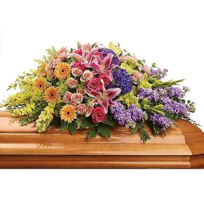 Colorful floral casket spray with pink lilies, roses, and purple blooms