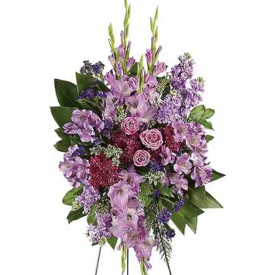 Standing spray of purple flowers with pink roses on a display easel