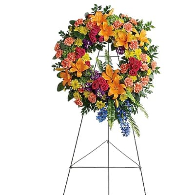Colorful funeral wreath on a metal easel with lilies, roses, and carnations