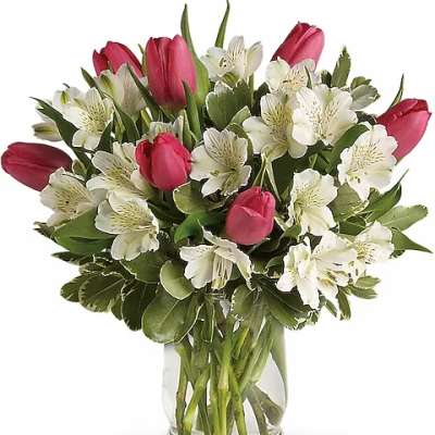 Pink tulips and white flowers arranged in a clear glass vase