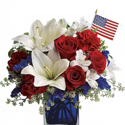 Red roses and white lilies in a blue glass vase with a small American flag
