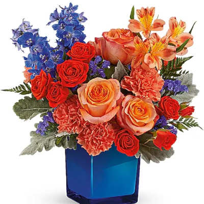 Mixed bouquet of roses, carnations, and blue flowers in a blue vase