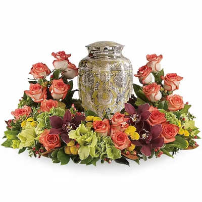 Coral roses and orchids arranged around a decorative urn