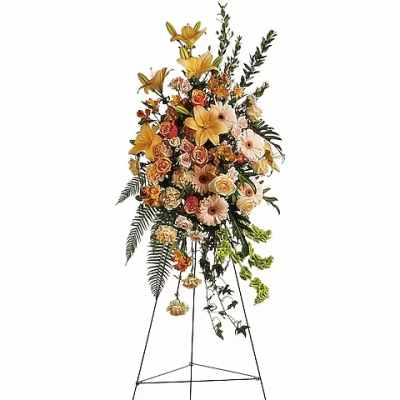 Tall floral standing spray with yellow lilies and peach roses on an easel