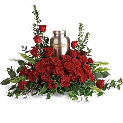Red roses arranged around a silver urn with greenery
