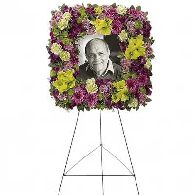 Standing floral wreath around a black-and-white portrait on an easel