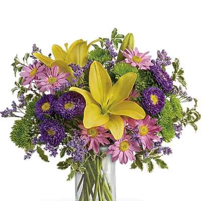 Bouquet of yellow lilies and pink daisies in a clear glass vase