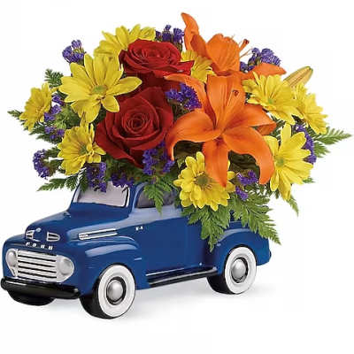 Blue toy truck filled with red, orange, and yellow flowers
