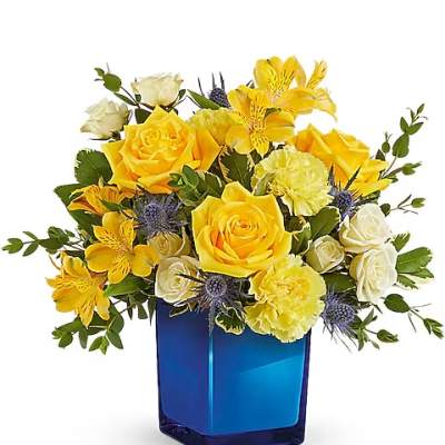 Yellow and white flower arrangement in a blue glass vase