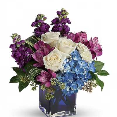 Purple and white floral arrangement in a blue glass vase