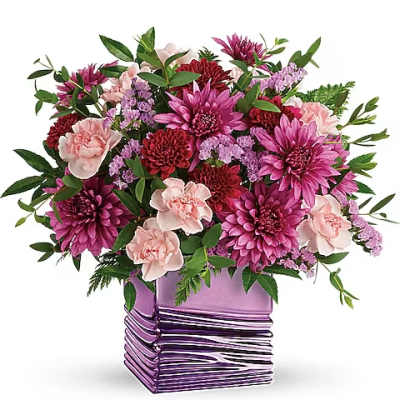 Pink and purple flower arrangement in a purple glass vase