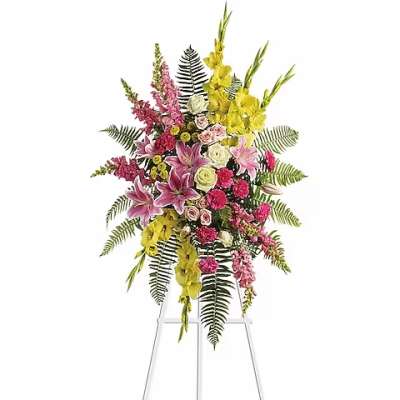 Tall standing floral spray with pink, yellow, and white flowers on a metal easel