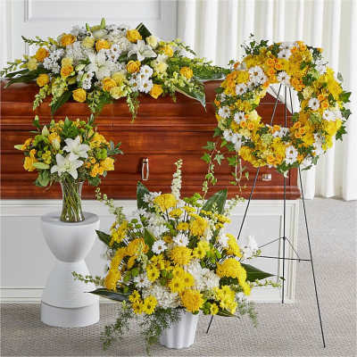 Yellow and white funeral floral arrangements around a casket