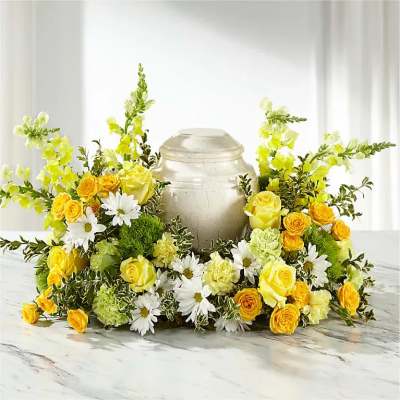 Yellow roses and white daisies arranged around a silver urn