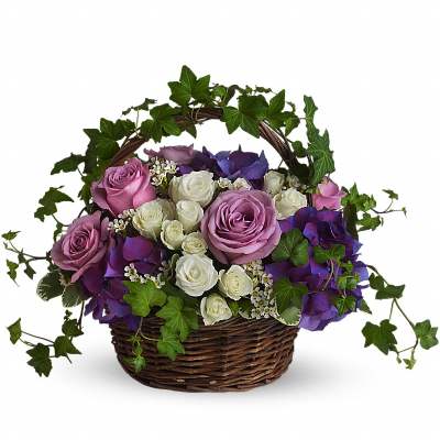 Lavender and white roses with purple hydrangeas and ivy arranged in a handled wicker basket