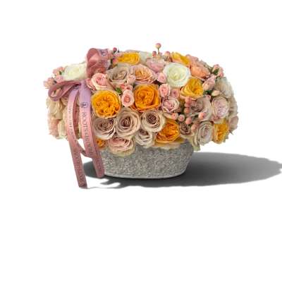 Low arrangement of pastel roses in a textured silver container with a pink ribbon