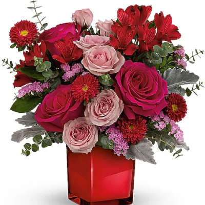 Red and pink mixed flower arrangement in a red glass vase