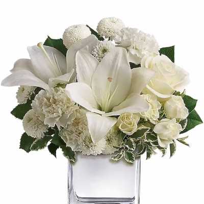 White lilies and roses arranged in a clear square vase