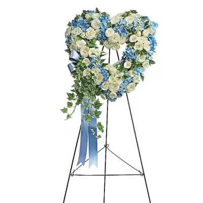 Heart-shaped floral wreath on a stand with blue and white flowers