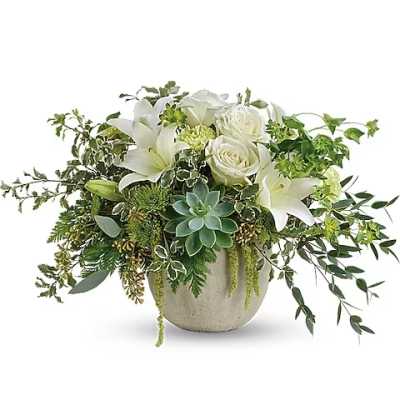 White roses and lilies in a round stone vase with trailing greenery