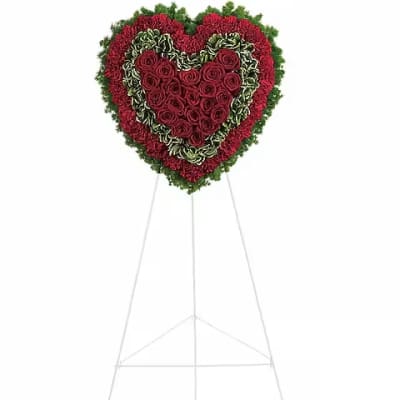 Heart-shaped floral standing spray with red roses and carnations on an easel