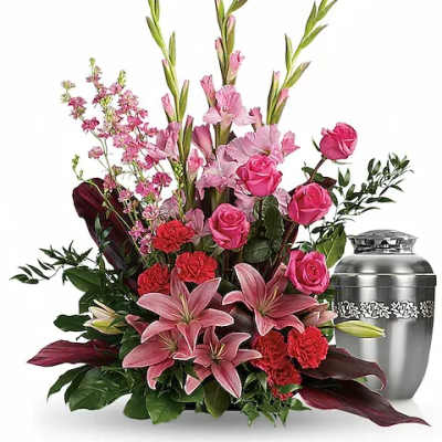Pink lilies and roses arranged beside a silver urn