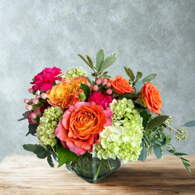 Orange roses and green hydrangeas in a glass vase