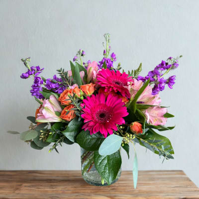 Bright mixed bouquet in a clear glass vase with pink and purple flowers