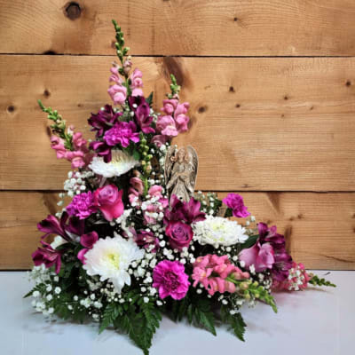 Pink and white floral arrangement with an angel figurine