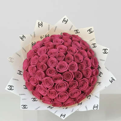 Bouquet of bright pink roses wrapped in Chanel-logo paper