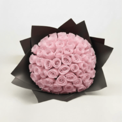 Bouquet of pale pink roses wrapped in dark paper
