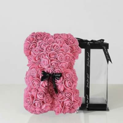 Pink rose teddy bear with a black ribbon on a display stand