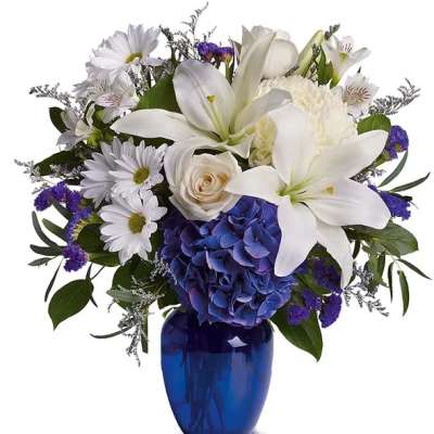 White lilies and daisies with blue hydrangea in a cobalt vase
