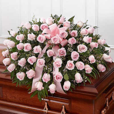 Pink rose casket spray with ribbon on a wooden coffin