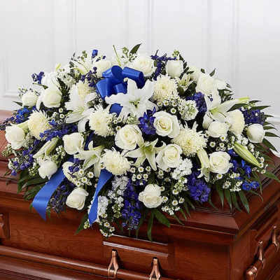 White and blue floral spray arranged on a wooden casket