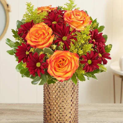 Bouquet of orange roses and burgundy daisies in a textured vase