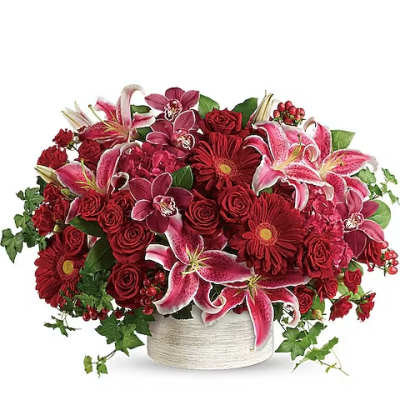 Red and pink floral arrangement in a white container