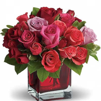 Bouquet of red, pink, and lavender roses in a square glass vase