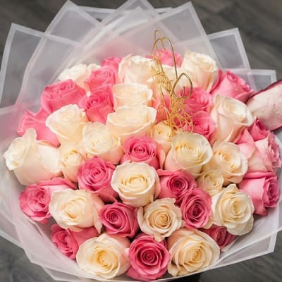 Bouquet of pink and cream roses wrapped in translucent paper